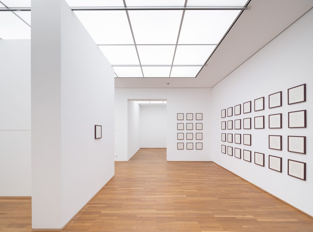 Weißer Raum mit 64 in Serien an den Wänden gehängten;, gerahmten Pastellkreide-Zeichungen auf Papier